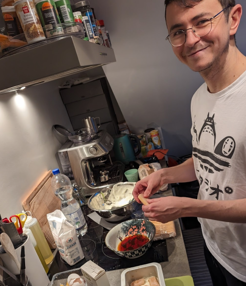 Un compañero sonriendo mientras cocina en una cocina ajetreada.